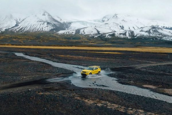 Self-drive car in Iceland crossing a remote volcanic landscape with mountains and glacial rivers